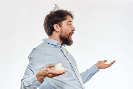 a man with a beard holds a cake in his hand on a light background birthday