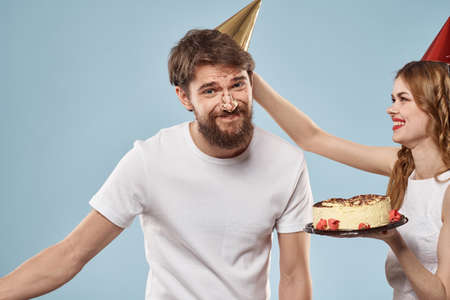 Young couple holiday fun birthday cake blue background