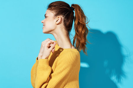 woman in yellow sweater fashion hairstyle casual wear Studio cropped view blue background