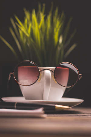 cup of coffee with glasses on a saucer and a wooden table flower in a pot in the backgroundの写真素材