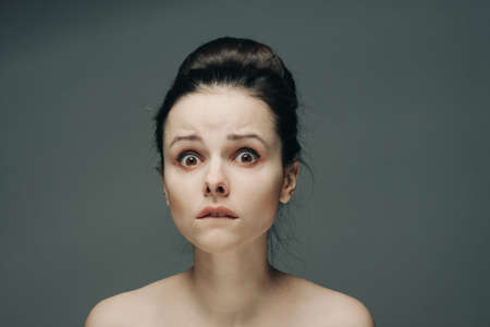 frightened womans face naked shoulders hairstyle gray background modelの写真素材