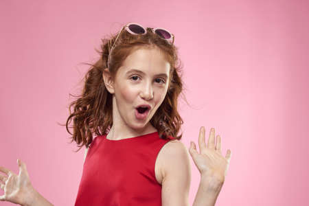 Cheerful little girl childhood dark glasses red dress lifestyle pink background