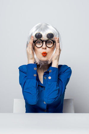 cheerful glamorous Woman in a White wig sits at the table with emotionの写真素材