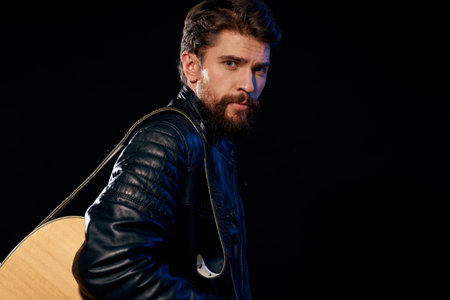 A man with a guitar in his hands leather jacket music performance rock star modern style dark backgroundの写真素材