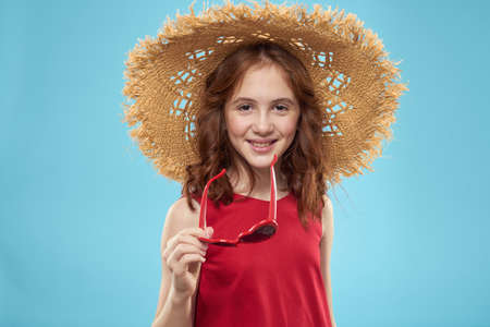 Girl in a beach Straw hat in sunglasses curly hair fun blue backgroundの写真素材