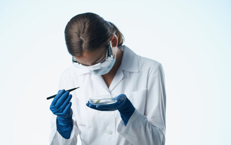 female laboratory assistant in a medical mask with a chemical element in a flask vaccinationの写真素材