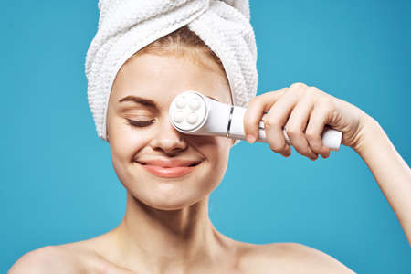 woman with a towel on her head holds massagers in her hands near the face cosmetology relaxの写真素材
