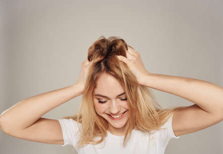 An energetic blonde touches the hair on her head with her handsの写真素材