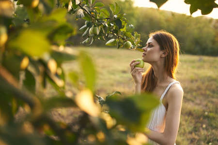 woman near the apple tree in a white dress outdoors in the garden