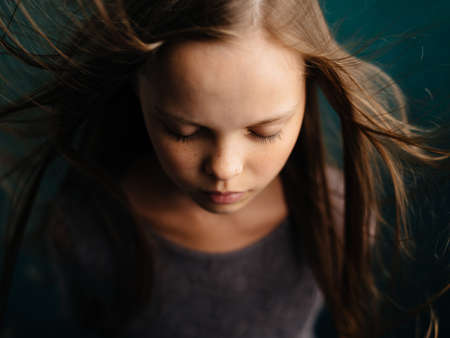 Portrait of a beautiful girl with closed eyes on a turquoise background and loose hair close-up cropped view.の写真素材