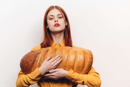 beautiful woman holding a loaf in her hands and bright makeup yellow shirt light backgroundの写真素材