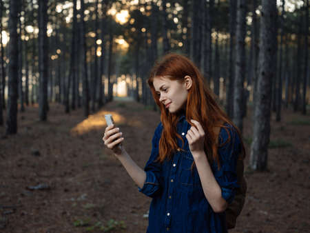 Happy woman in pine forest with mobile phone navigator tourism modelの写真素材