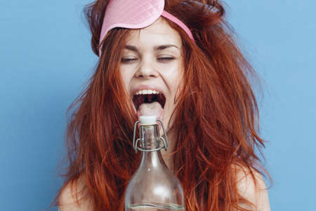 woman with red hair bottle alcohol hangover sleep maskの写真素材