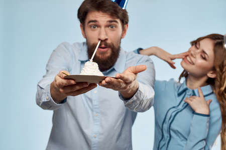 Party man and woman with birthday cake at corporate party. blue backgroundの写真素材