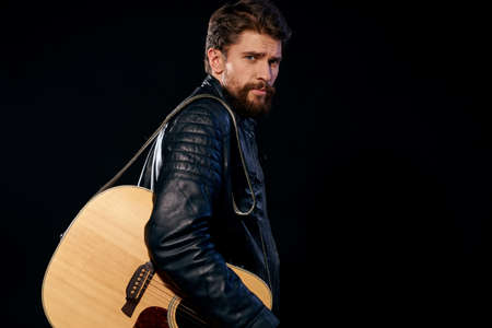 A man with a guitar in his hands leather jacket music performance rock star modern style dark backgroundの写真素材
