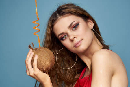 woman with coconut cocktail in hands wavy hair bright makeup lifestyle studio summer vacationの写真素材