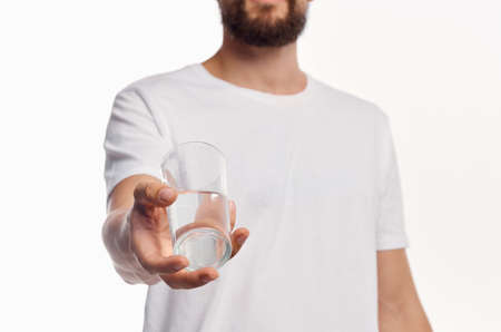 a glass of clean water in the hand of a man in a light shirt cropped viewの写真素材