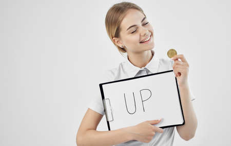 cheerful woman in a white shirt holds a folder with the inscription upward cryptocurrency Bitcoin internet Finlandの写真素材
