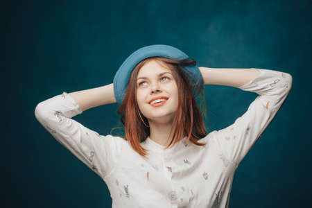 emotional woman in blue hat gesturing with hands red hair blonde sweaterの写真素材