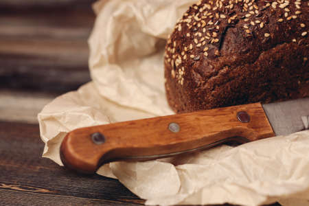 rye bread baking on paper packaging wooden table and sharp knife