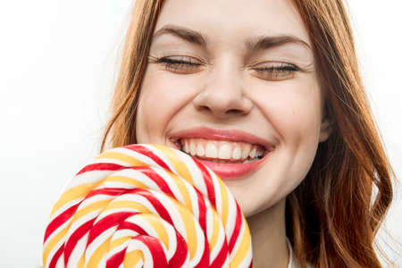 pretty woman licks colorful lollipop sweet candy delightの写真素材