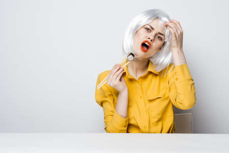 glamorous woman sitting at the table chopsticks sushi skewed restの写真素材