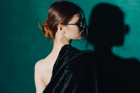 sexy woman in sunglasses red hair green background black sweater