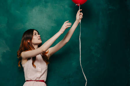 woman holding an inflatable red ball in her hand on a green background holidays giftsの写真素材