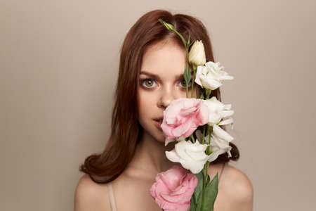 Happy woman with a bouquet of light flowers on a beige background naked shoulders model red hair beautiful faceの写真素材