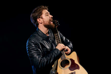 A man with a guitar in his hands leather jacket music performance rock star modern style dark...