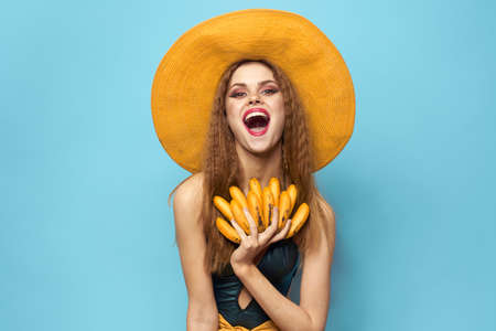Woman in swimsuit hat exotic fruits summer fun blue backgroundの写真素材