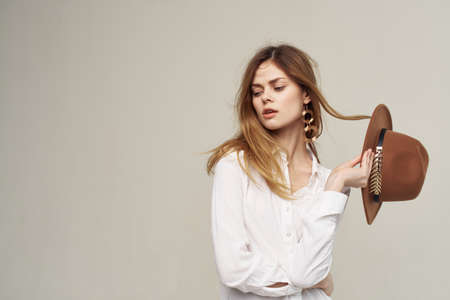 elegant woman in white shirt holding hat in her hands fashion light backgroundの写真素材