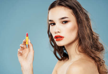 Sexy brunette with red lipstick in her hands on a blue background nude shoulders cropped view