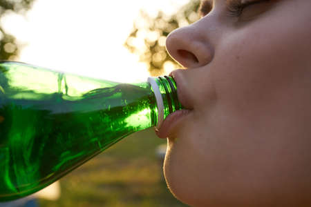 happy woman with bottle of water for invitation in garden close-up cropped viewの写真素材