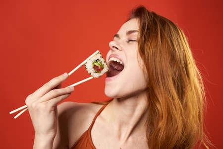 pretty woman red haired woman sushi chopsticks diet food red backgroundの写真素材
