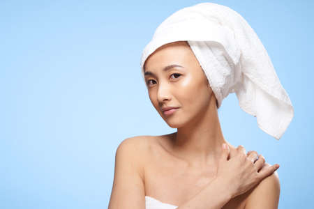 pretty asian woman clean skin care towel on head blue backgroundの写真素材
