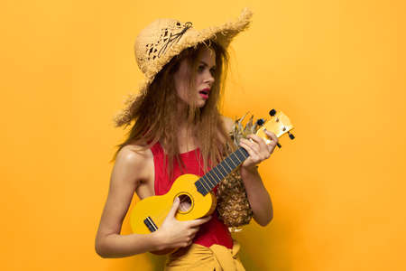 Woman holding Ukulele straw hat lifestyle Exotic yellow backgroundの写真素材