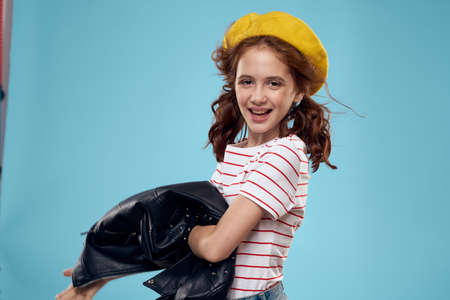 Cheerful cute girl in yellow hat clothes studio blue backgroundの写真素材