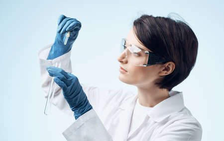 female laboratory assistant with a flask in his hands glasses on his face and a medical gown