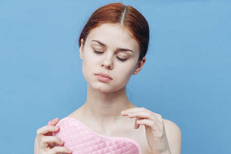pretty woman holding a pink sleep mask on a blue background Copy Space