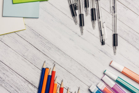 markers pencils pens on a wooden table and colored paper office stationery