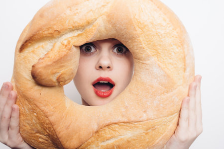 woman looking through the middle of a round loaf bright makeup close-upの写真素材