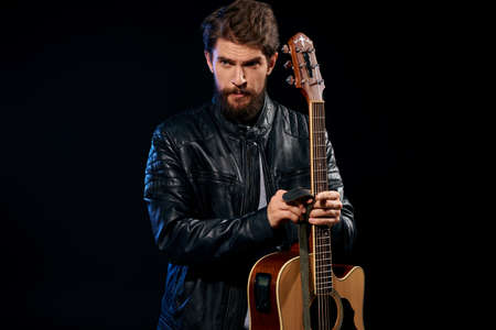 A man with a guitar in his hands leather jacket music performance rock star modern style dark...