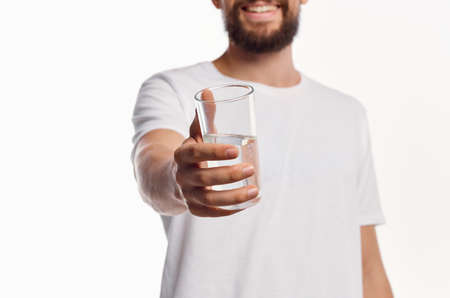 a glass of clean water in the hand of a man in a light shirt cropped viewの写真素材