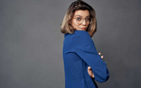 cheerful pretty woman with glasses blue shirt fashion gray background