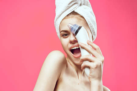 woman with towel on head massagers in hands skin care cropped view pink backgroundの写真素材