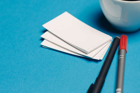 blank business cards on blue background and coffee cup gel pensの写真素材
