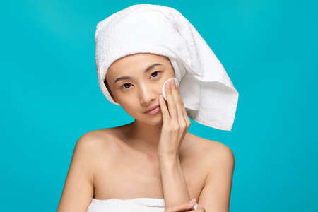 woman of asian appearance naked shoulders clear skin cotton pad blue backgroundの写真素材