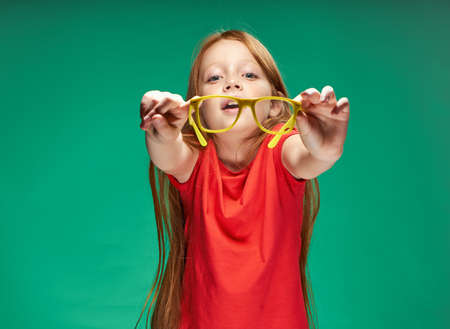 cute red-haired girl emotions yellow glasses training green backgroundの写真素材