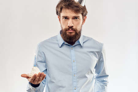 A man with a cake plate and in a blue shirt on a light background birthday party corporate capの写真素材